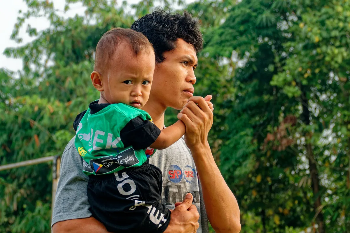 Ayah menggendong anaknya sambil berpikir